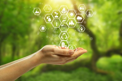 Image of Environmental protection. Woman holding many different icons in nature, closeup