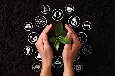 Image of Environmental protection. Woman holding young green seedling in soil, top view. Many different icons around her hands