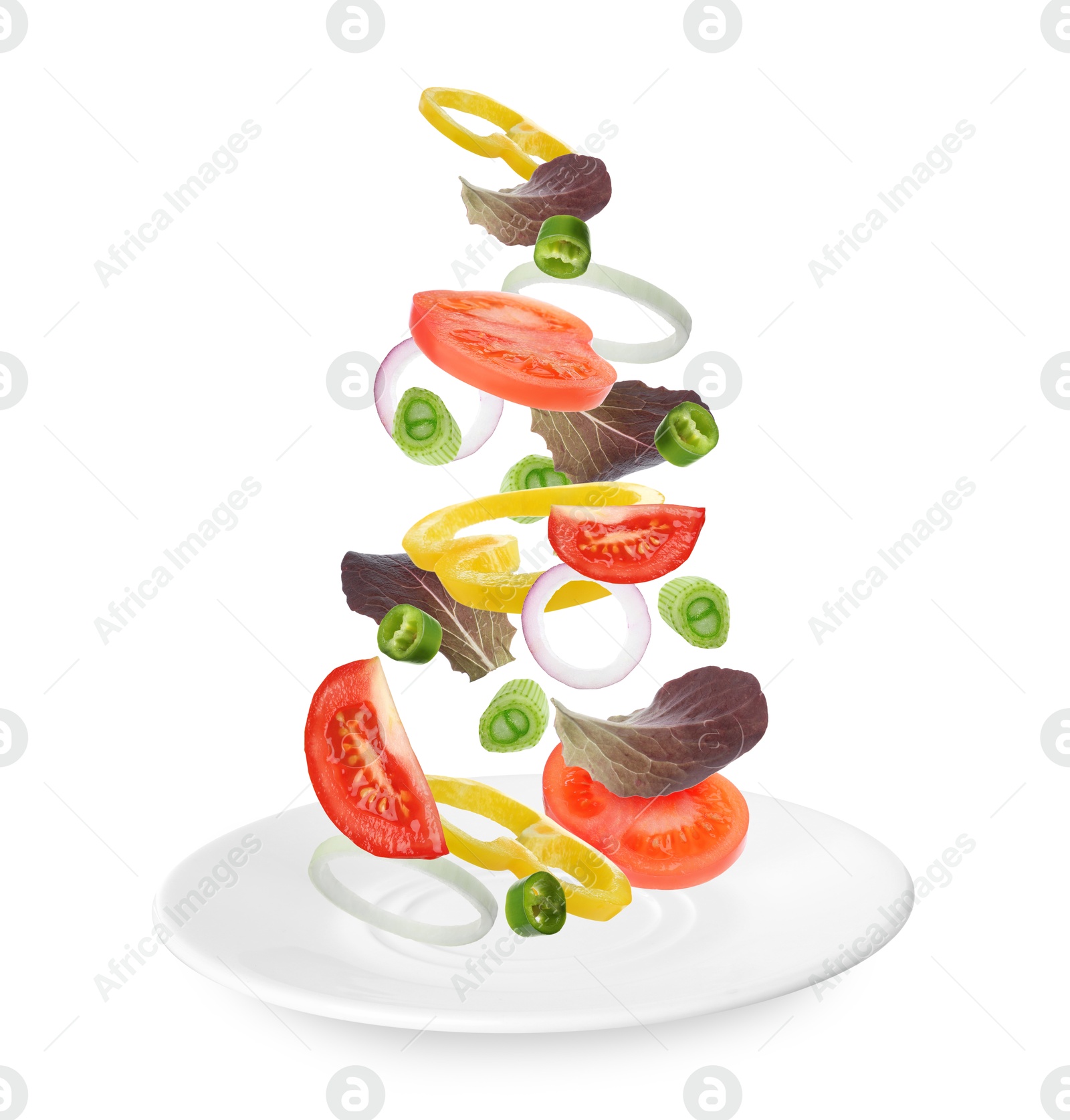 Image of Fresh vegetables for salad falling onto plate on white background