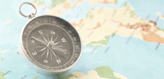 Image of Compass on world map, closeup. Banner design with space for text