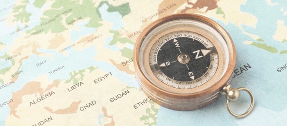 Image of Compass on world map, closeup. Banner design with space for text