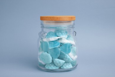 Image of Many blue color candies in glass jar on light blue background