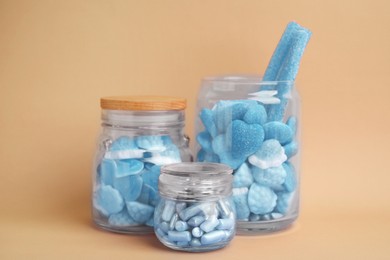 Many blue color candies in glass jars on beige background