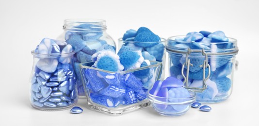 Many blue color candies in glass jars on white background. Banner design