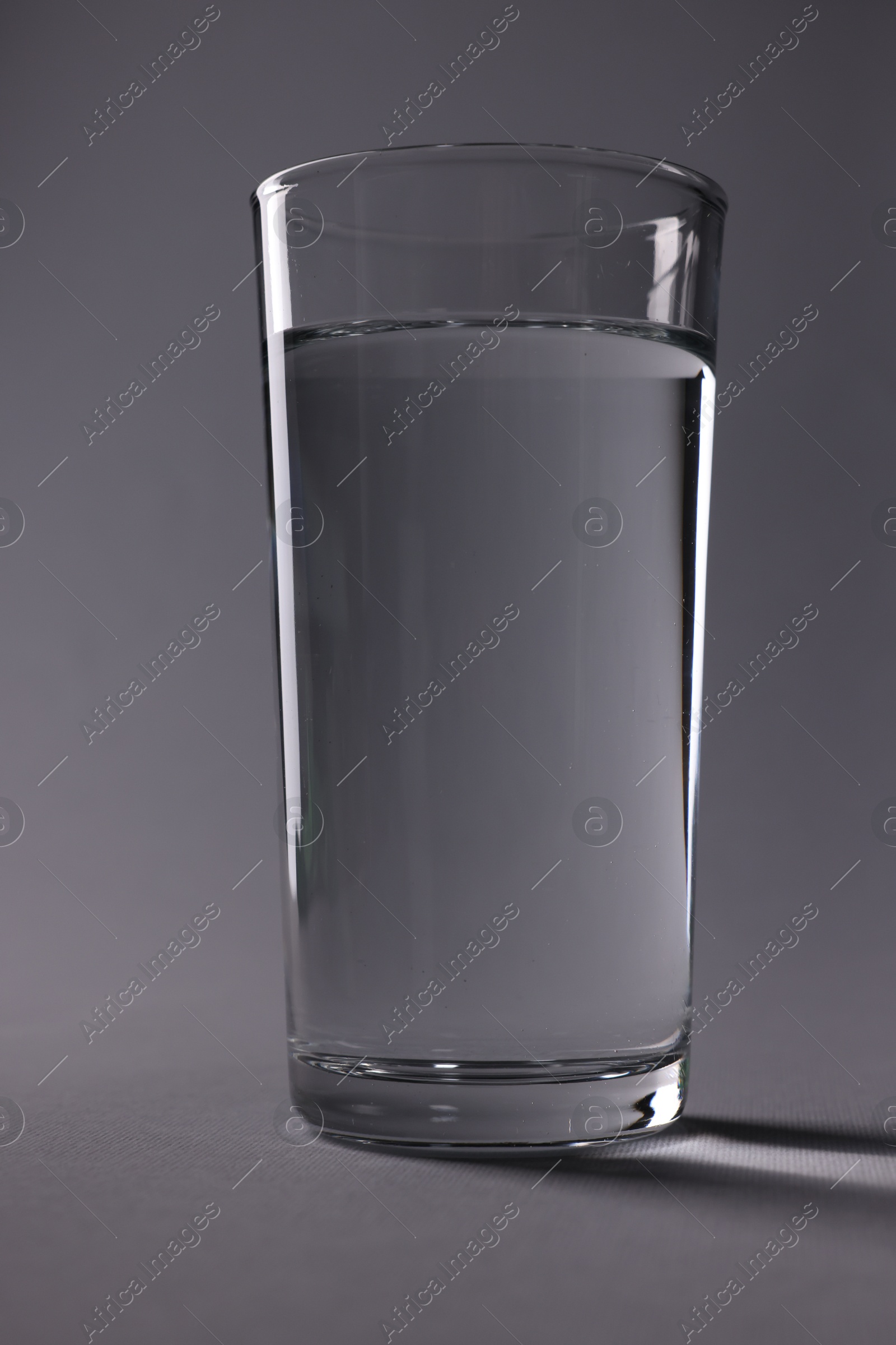 Photo of Glass of fresh water on grey background