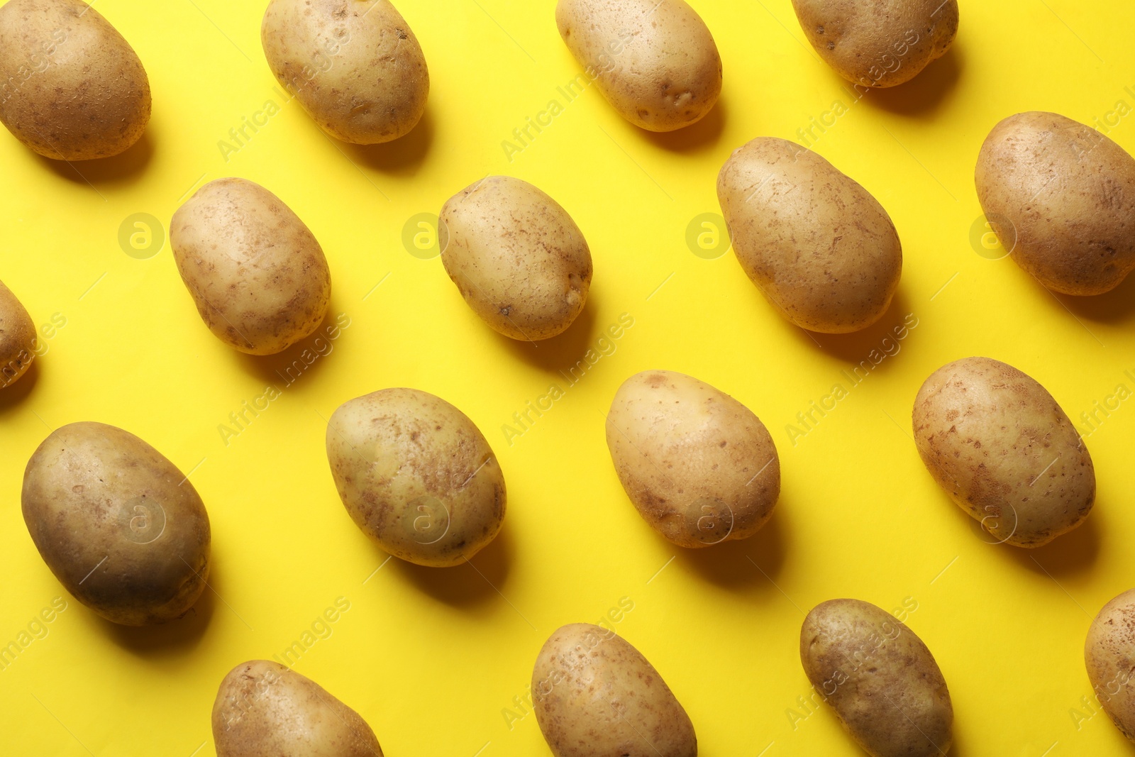 Photo of Many fresh potatoes on yellow background, flat lay