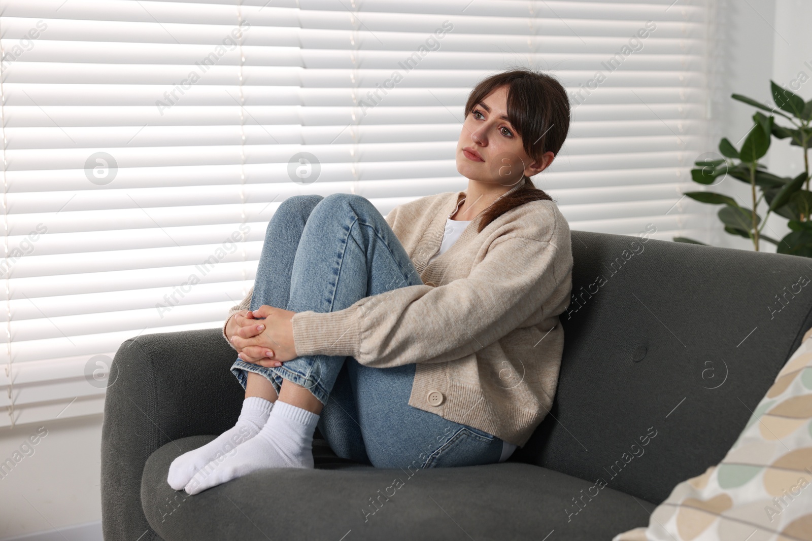 Photo of Loneliness concept. Sad woman sitting on sofa at home