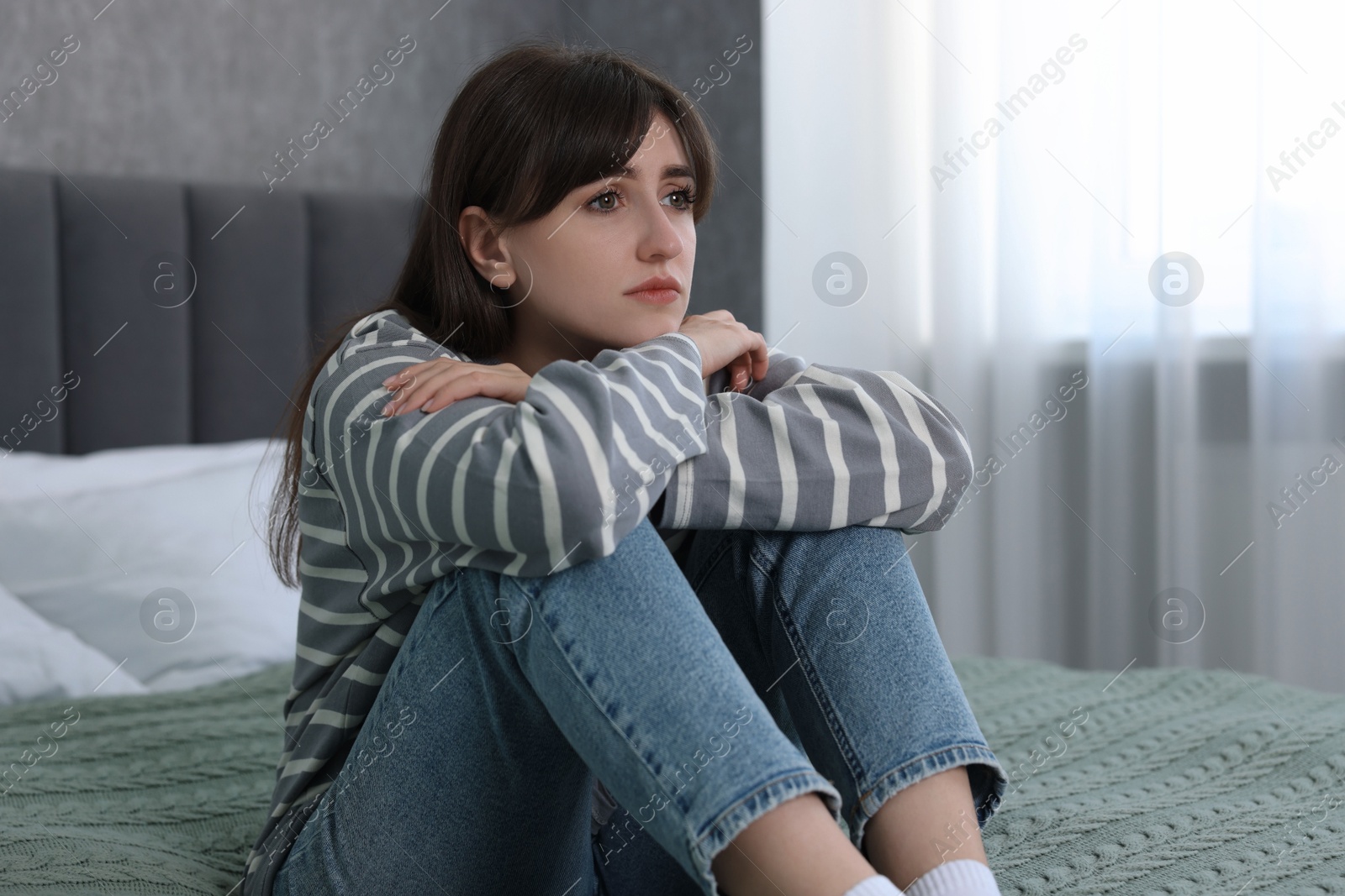 Photo of Loneliness concept. Sad woman sitting on bed at home