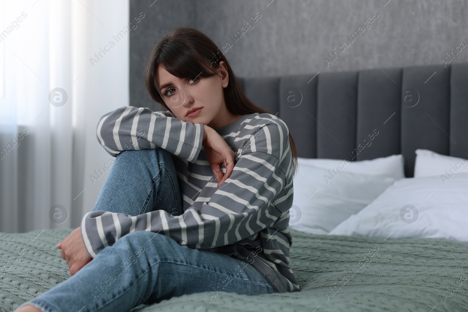 Photo of Loneliness concept. Sad woman sitting on bed at home, space for text