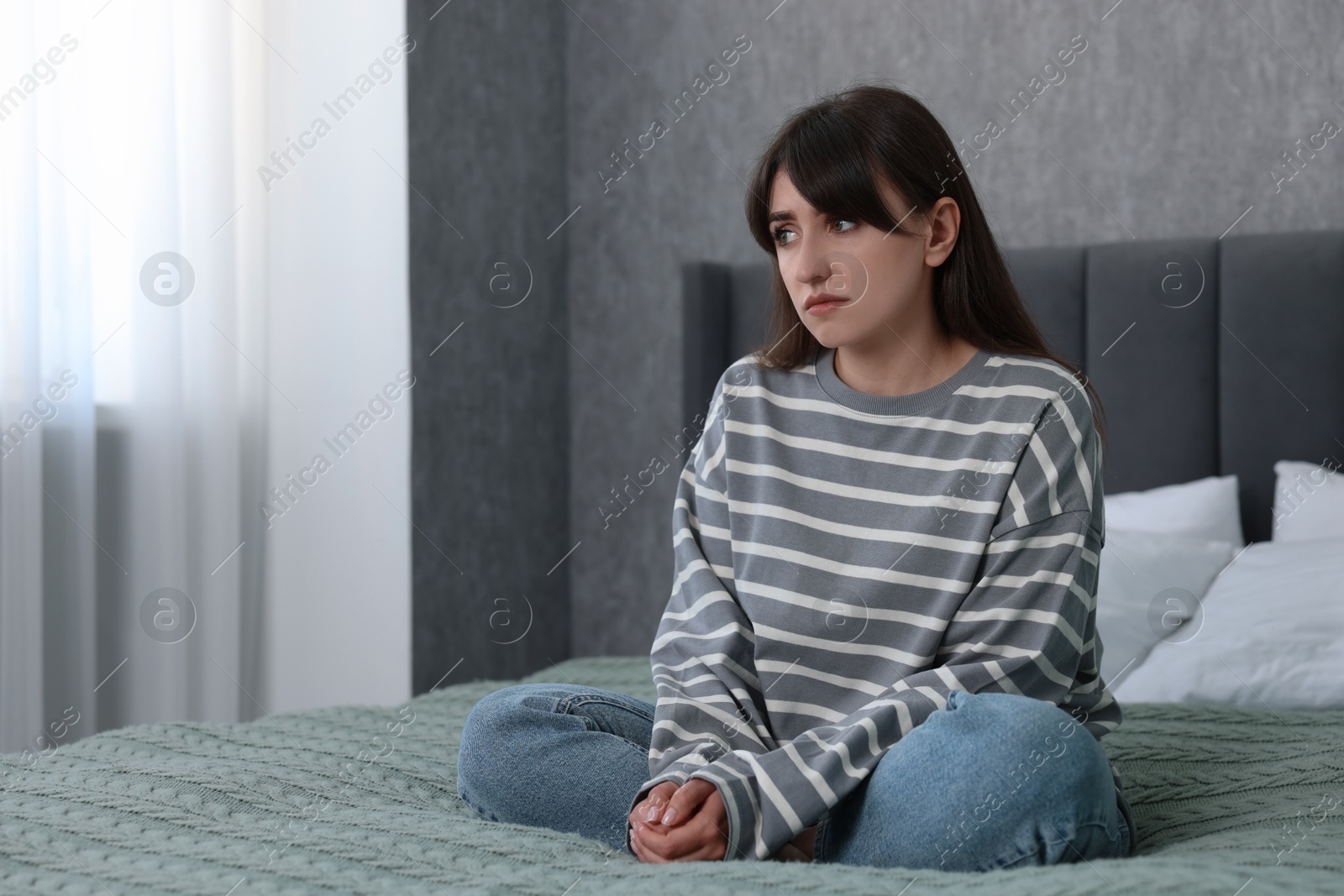 Photo of Loneliness concept. Sad woman sitting on bed at home, space for text