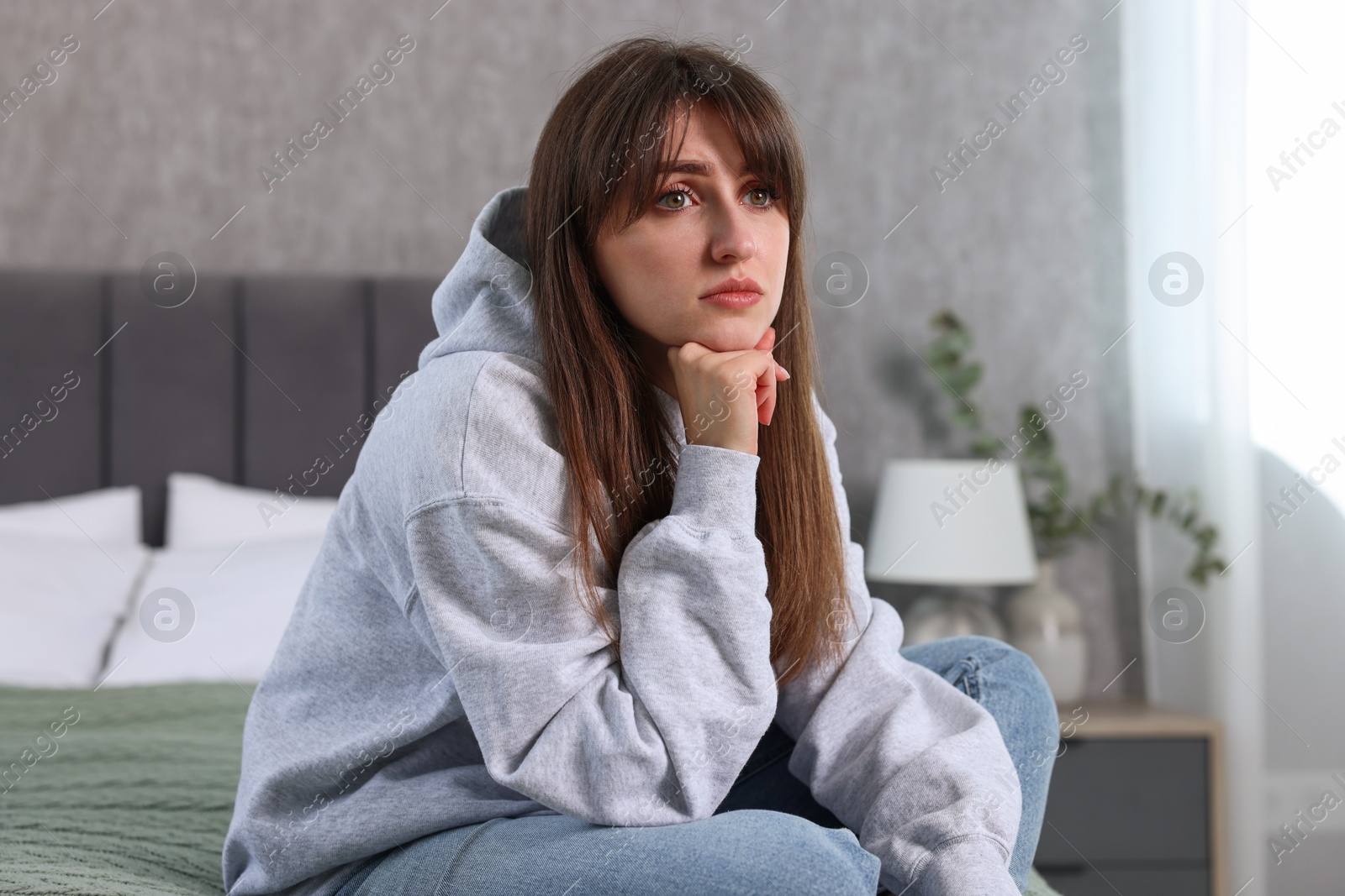 Photo of Loneliness concept. Sad woman sitting on bed at home