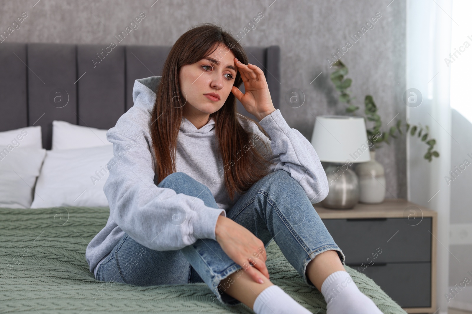 Photo of Loneliness concept. Sad woman sitting on bed at home