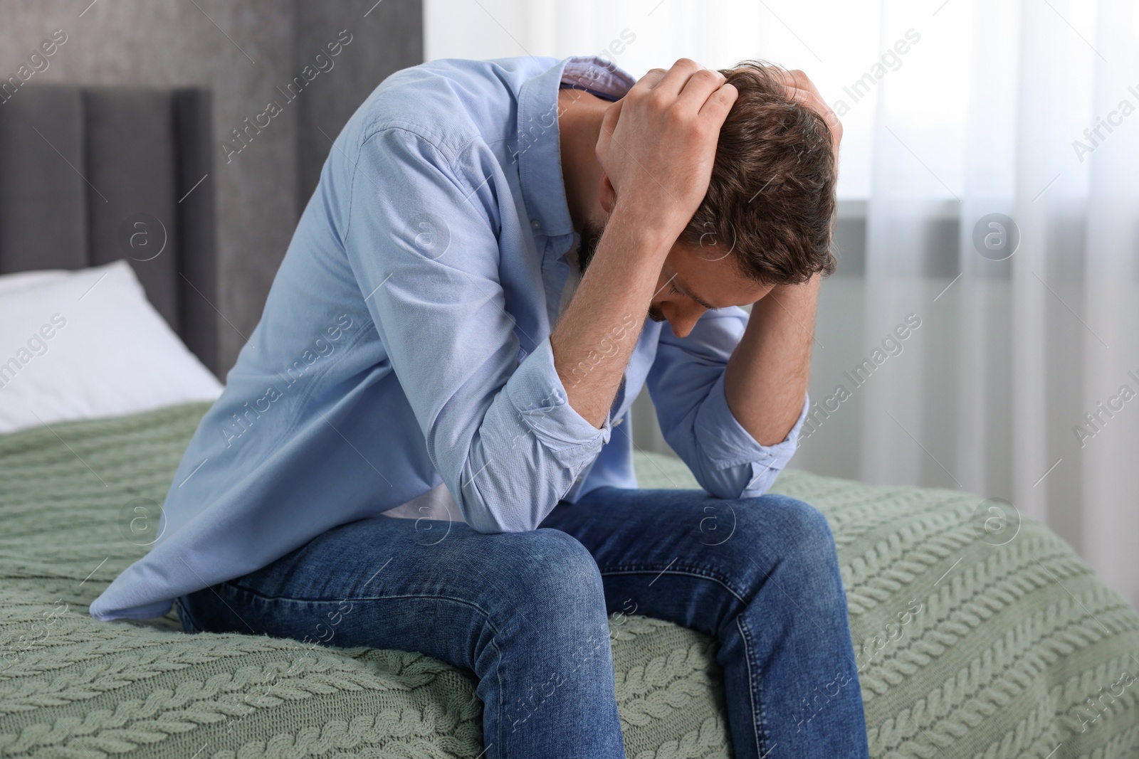 Photo of Loneliness concept. Sad man sitting on bed at home