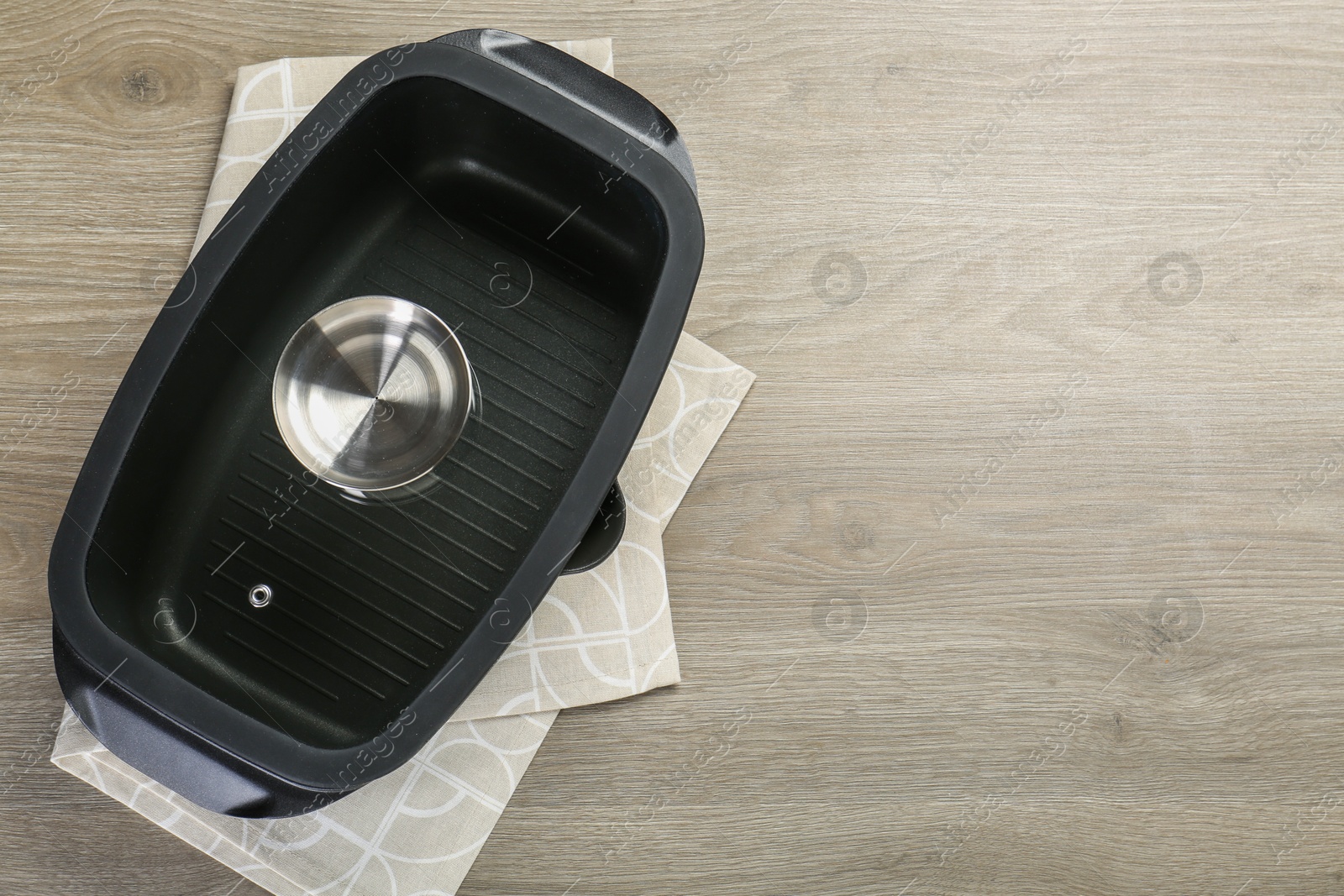 Photo of Black pot with glass lid on wooden table, top view. Space for text