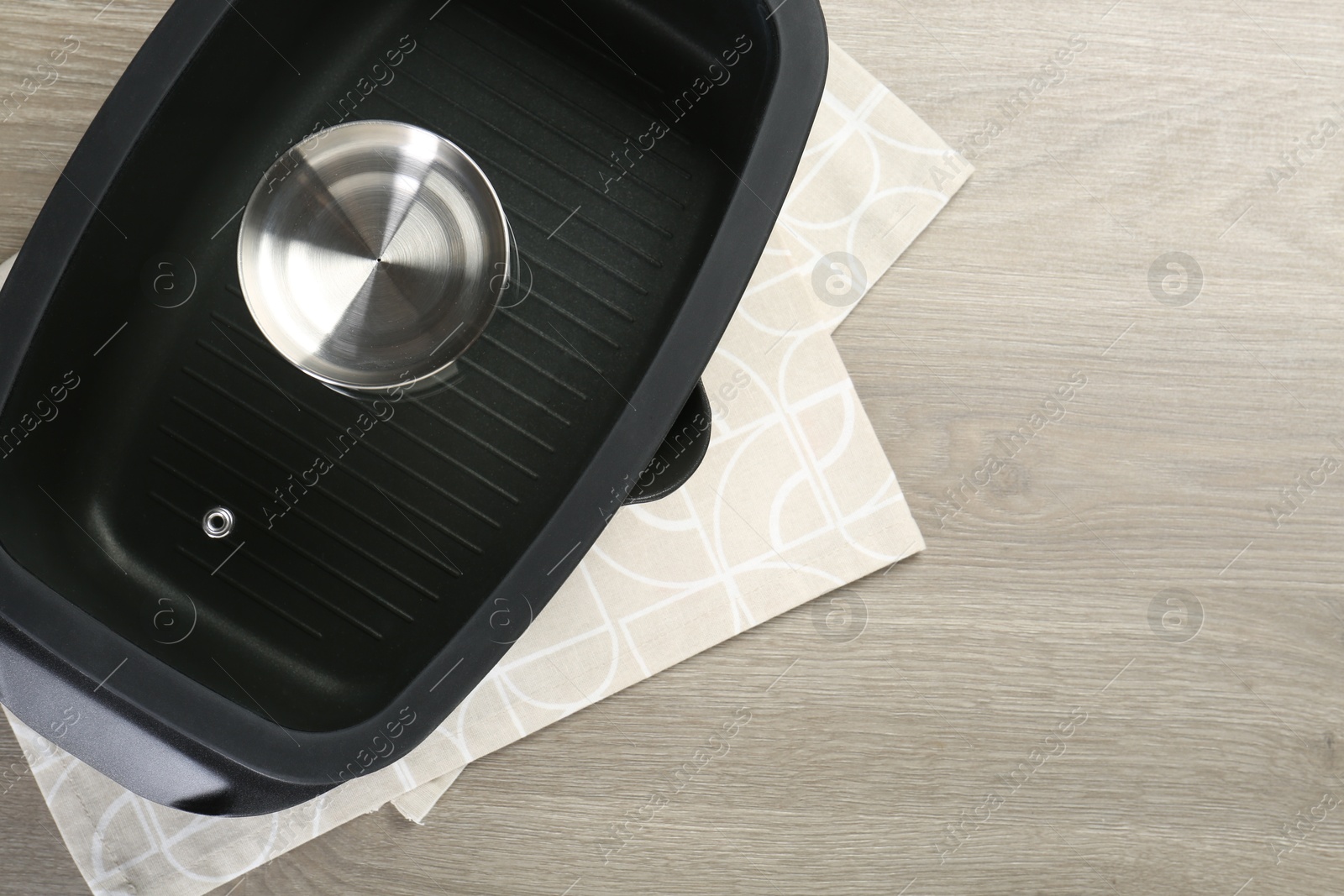 Photo of Black pot with glass lid on wooden table, top view. Space for text