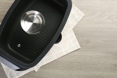 Photo of Black pot with glass lid on wooden table, top view. Space for text