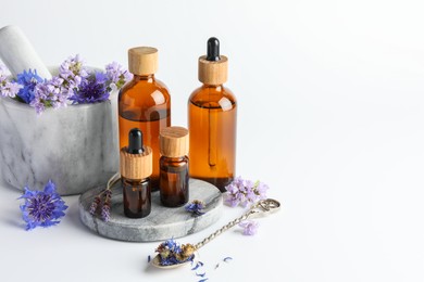 Photo of Aromatherapy. Different essential oils, flowers, mortar and pestle on white background, space for text