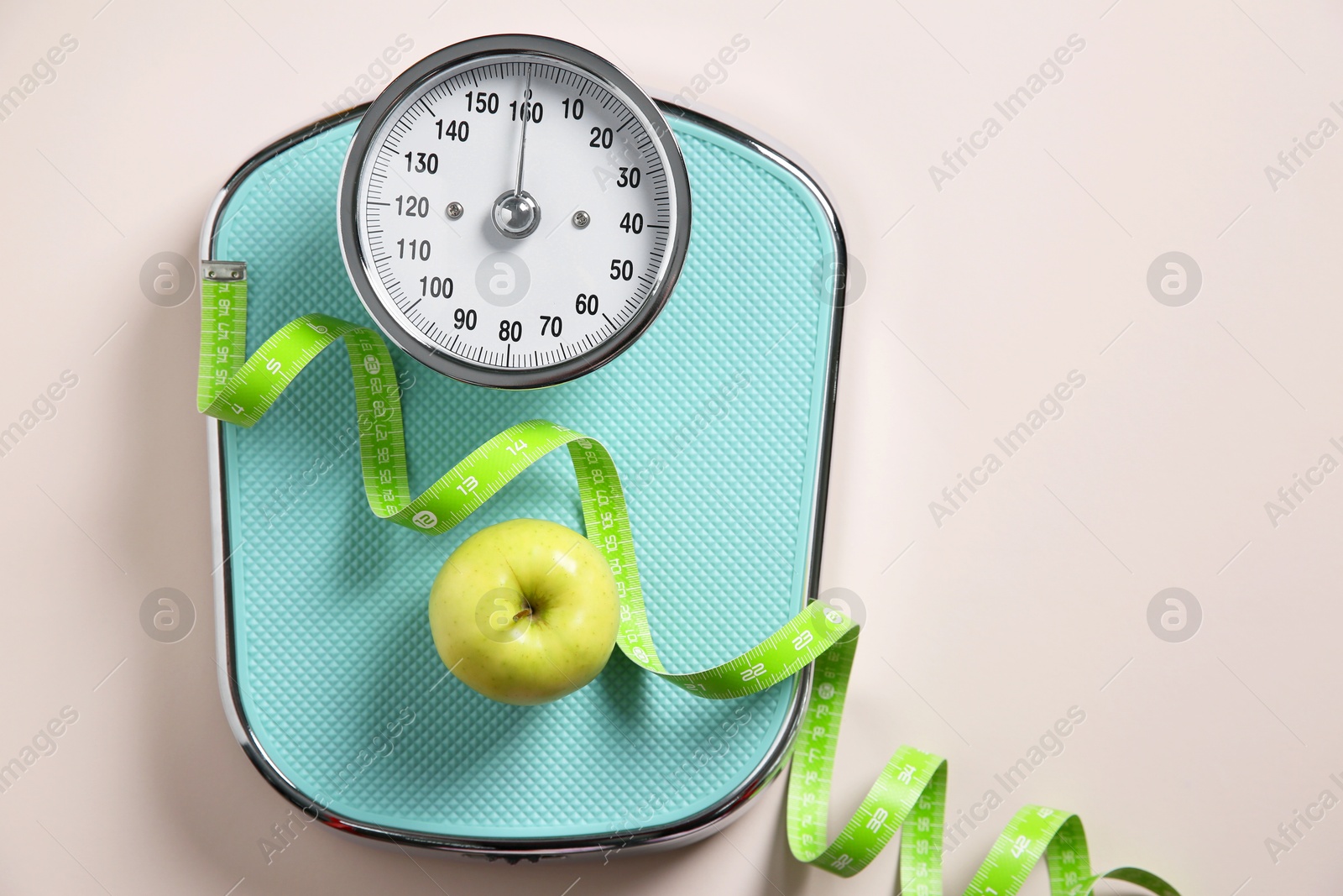 Photo of Scale, measuring tape and fresh apple on beige background, top view. Space for text