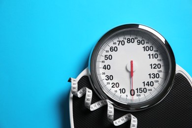 Photo of Scale and measuring tape on light blue background, top view. Space for text