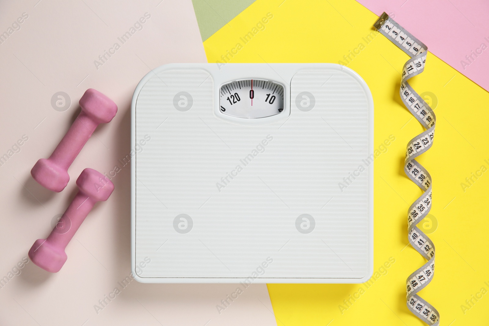 Photo of Scale, dumbbells and measuring tape on color background, flat lay