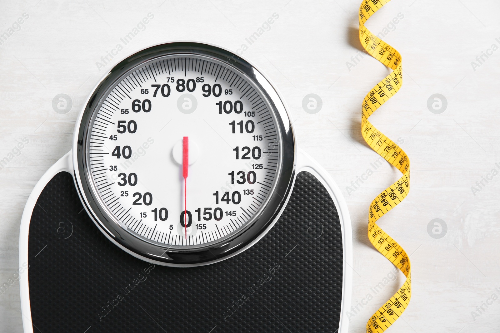 Photo of Scale and measuring tape on white wooden background, flat lay