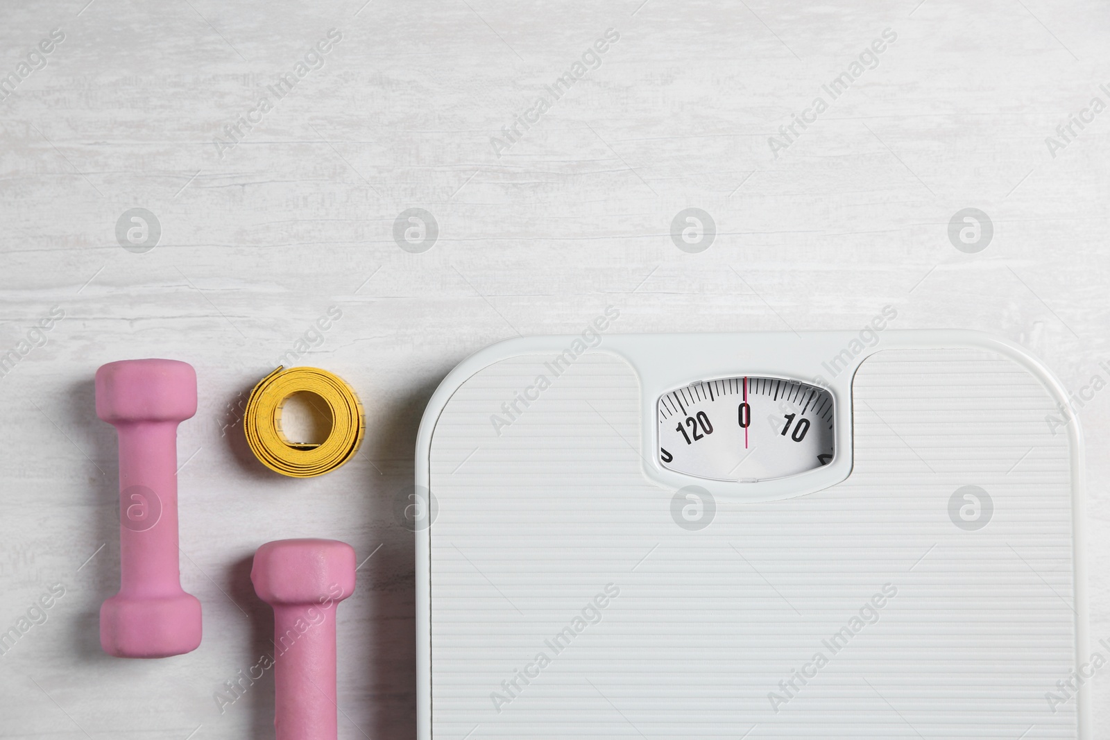 Photo of Bathroom scale, measuring tape and dumbbells on white wooden background, flat lay. Space for text