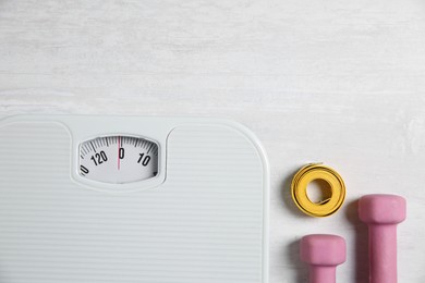 Photo of Bathroom scale, measuring tape and dumbbells on white wooden background, flat lay. Space for text