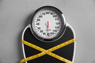 Photo of Scale tied with measuring tape on grey textured background, top view