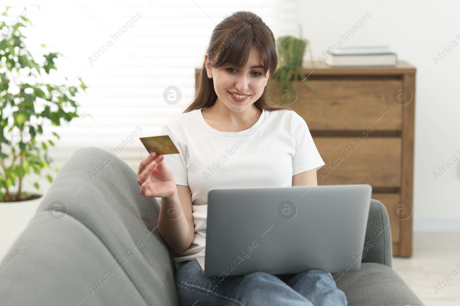 Photo of Online banking. Smiling woman with credit card and laptop paying purchase at home