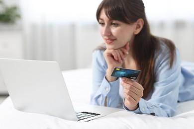 Photo of Online banking. Smiling woman with credit card and laptop paying purchase at home, selective focus