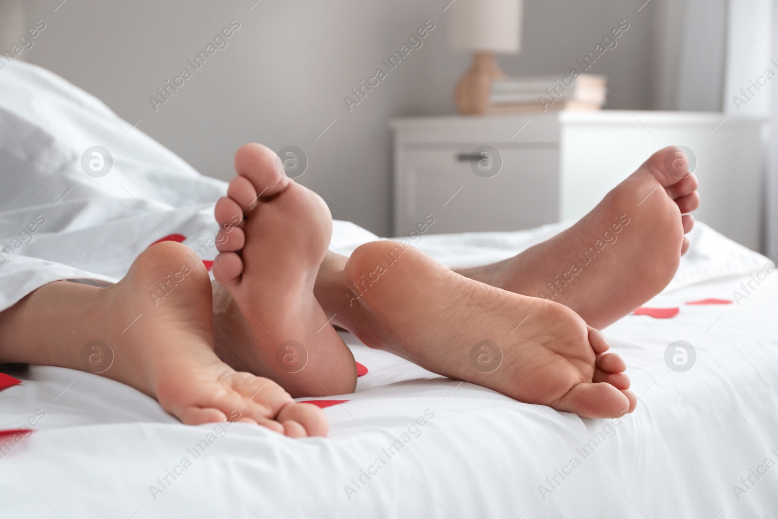 Photo of Couple lying in bed with red hearts, closeup