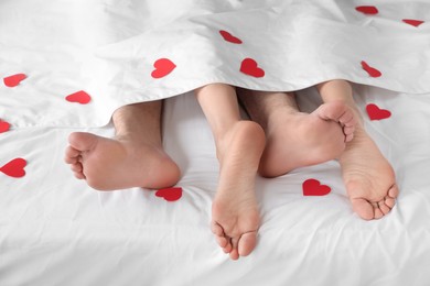 Photo of Couple lying in bed with red hearts, closeup