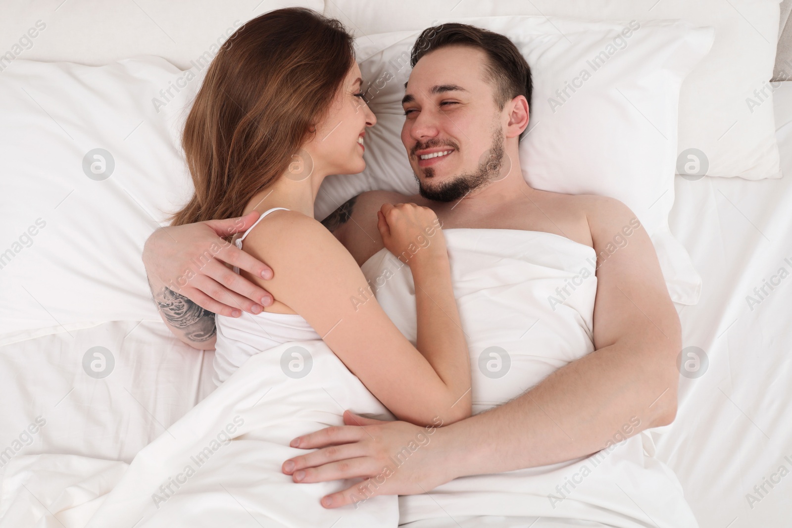 Photo of Lovely couple enjoying time together in bed at morning, top view