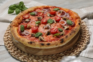Photo of Delicious pizza with vegetables, salami, mushrooms and basil on wooden table, closeup