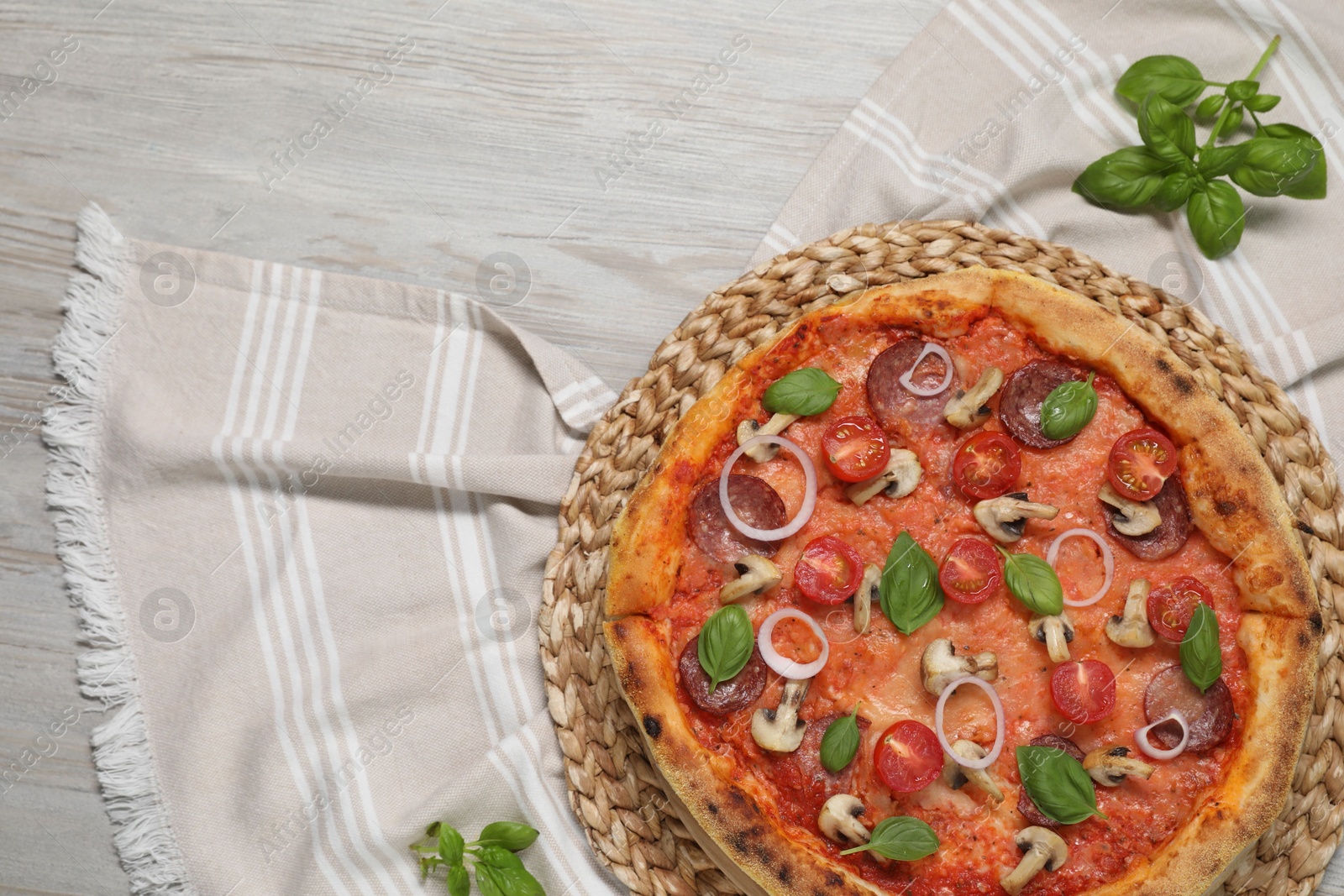 Photo of Delicious pizza with vegetables, salami, mushrooms and basil on wooden table, top view. Space for text