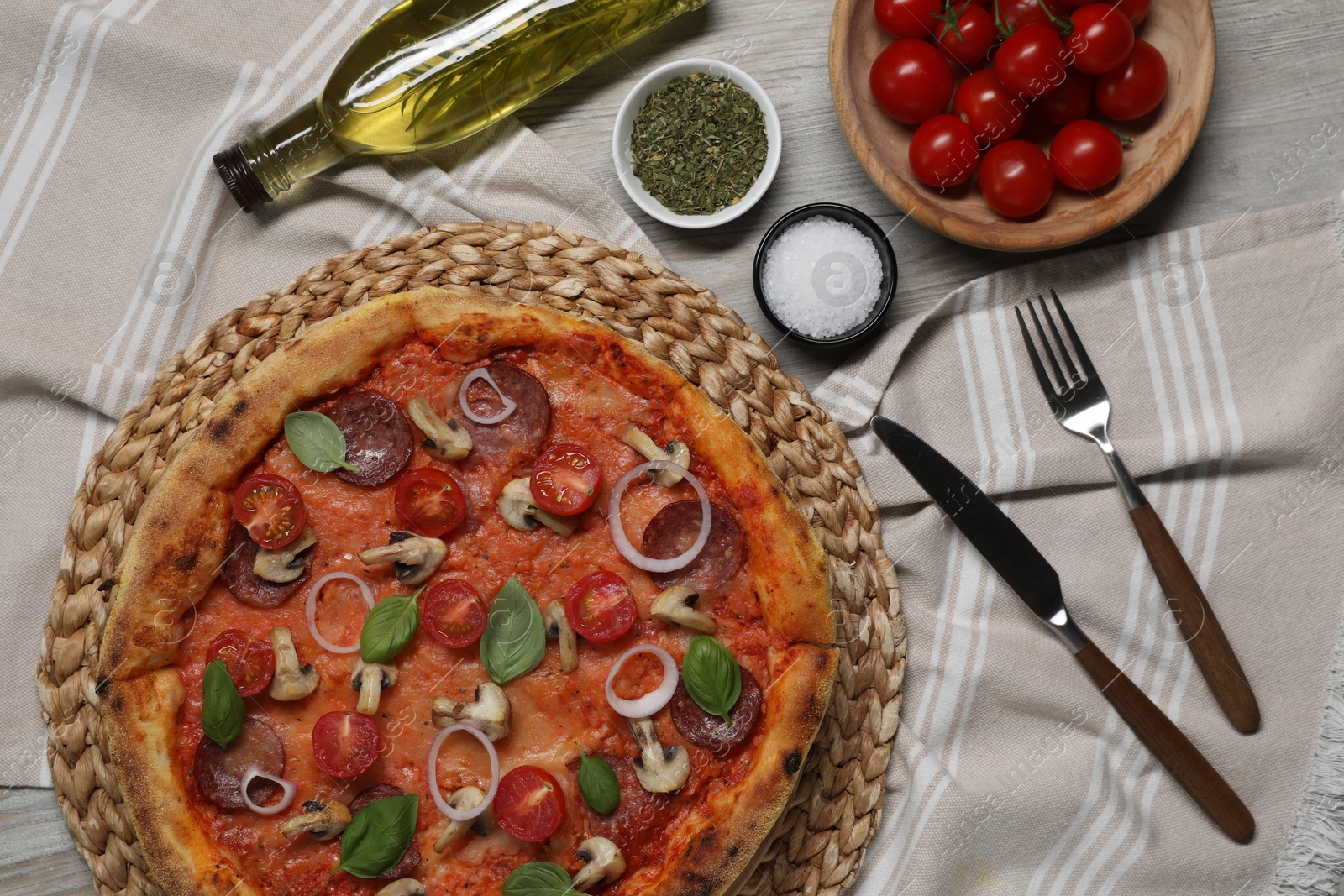 Photo of Delicious pizza with vegetables, salami, mushrooms and basil served on wooden table, flat lay