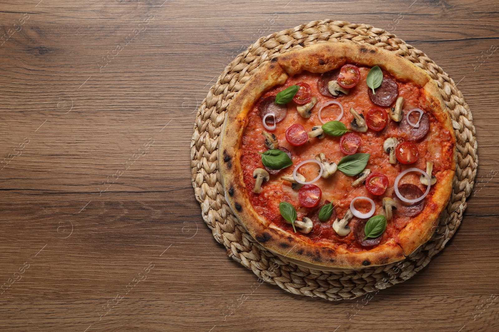 Photo of Delicious pizza with vegetables, salami, mushrooms and basil on wooden table, top view. Space for text