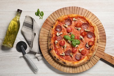 Photo of Delicious pizza with tomatoes, salami, mushrooms and basil on wooden table, flat lay