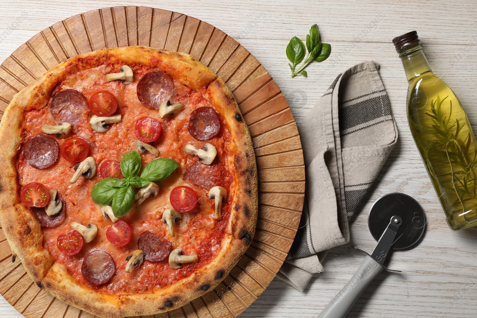 Photo of Delicious pizza with tomatoes, salami, mushrooms and basil on wooden table, flat lay