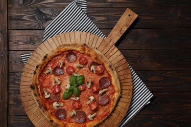 Photo of Delicious pizza with tomatoes, salami, mushrooms and basil on wooden table, top view