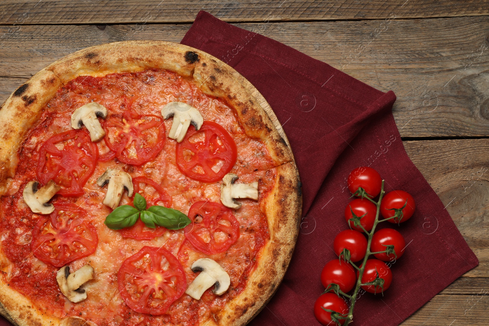 Photo of Delicious pizza with tomatoes, mushrooms and basil on wooden table, flat lay