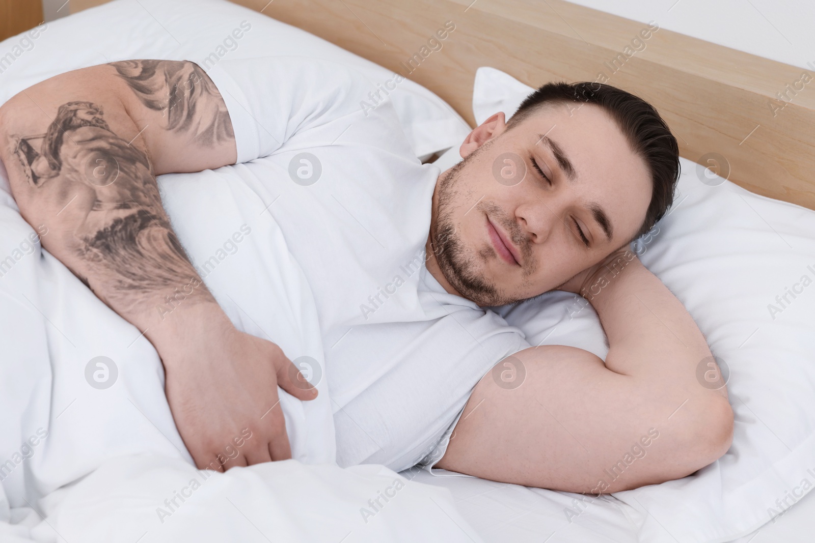 Photo of Bedtime. Handsome man sleeping in bed indoors