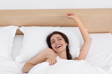 Photo of Bedtime. Happy woman lying in bed indoors