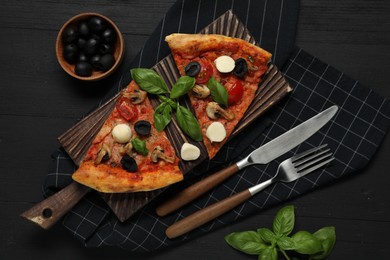 Photo of Pieces of tasty pizza served on black wooden table, flat lay