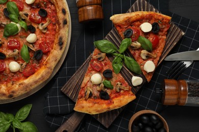 Photo of Tasty pizza served on black wooden table, flat lay