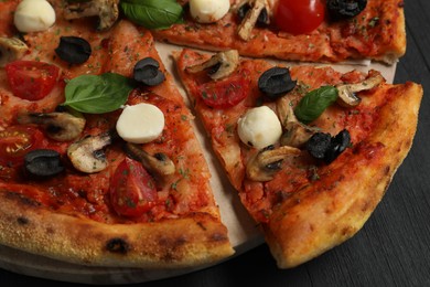 Photo of Tasty pizza on black wooden table, closeup