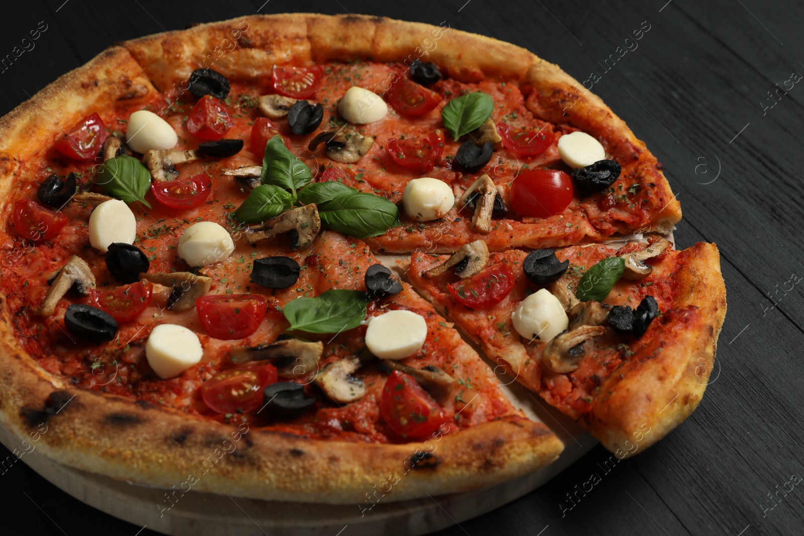 Photo of Tasty pizza on black wooden table, closeup