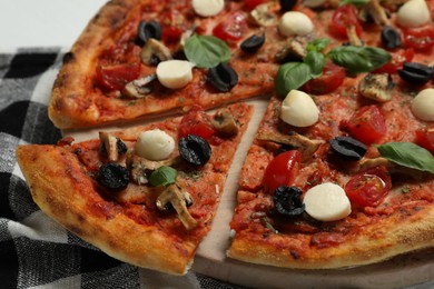 Photo of Tasty pizza with mozzarella, basil, tomatoes and olives on table, closeup