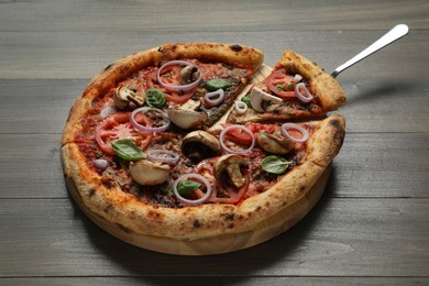 Photo of Tasty pizza with mushrooms, basil and tomatoes on wooden table, closeup