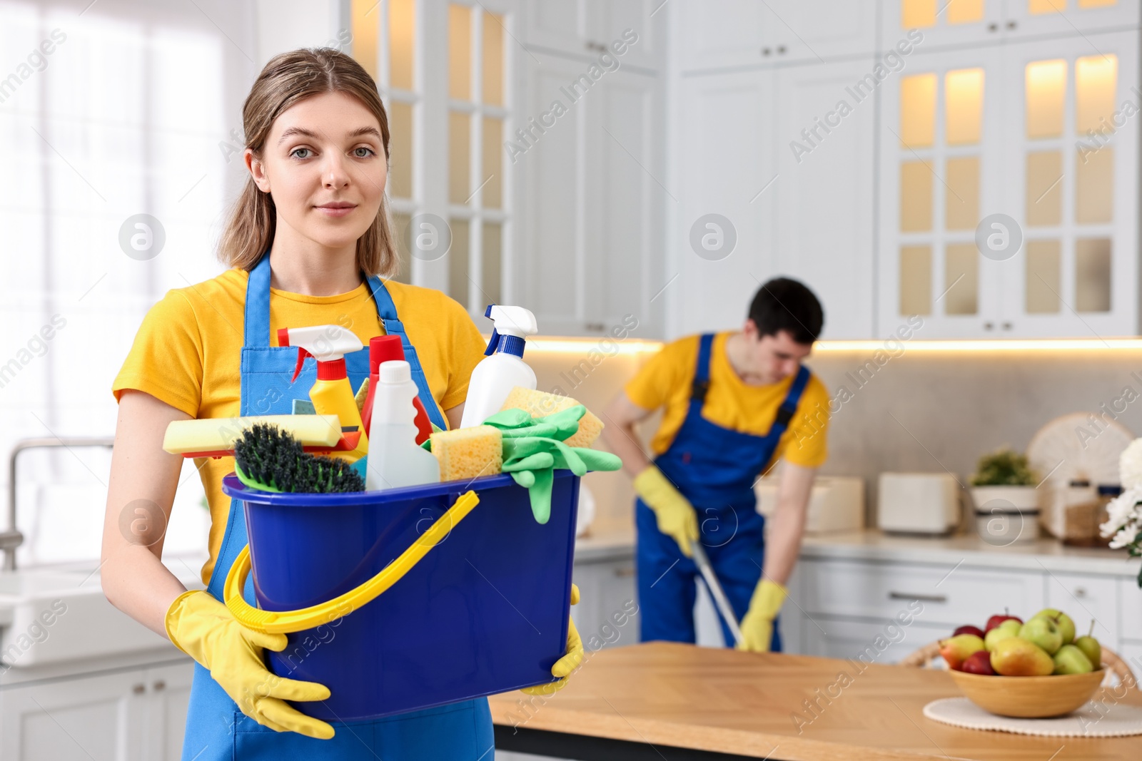 Photo of Cleaning service worker holding bucket with supplies in kitchen